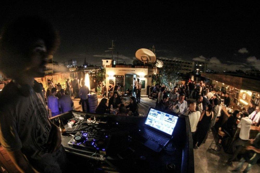 DJ aux platines sur une terrasse animée, le soir
