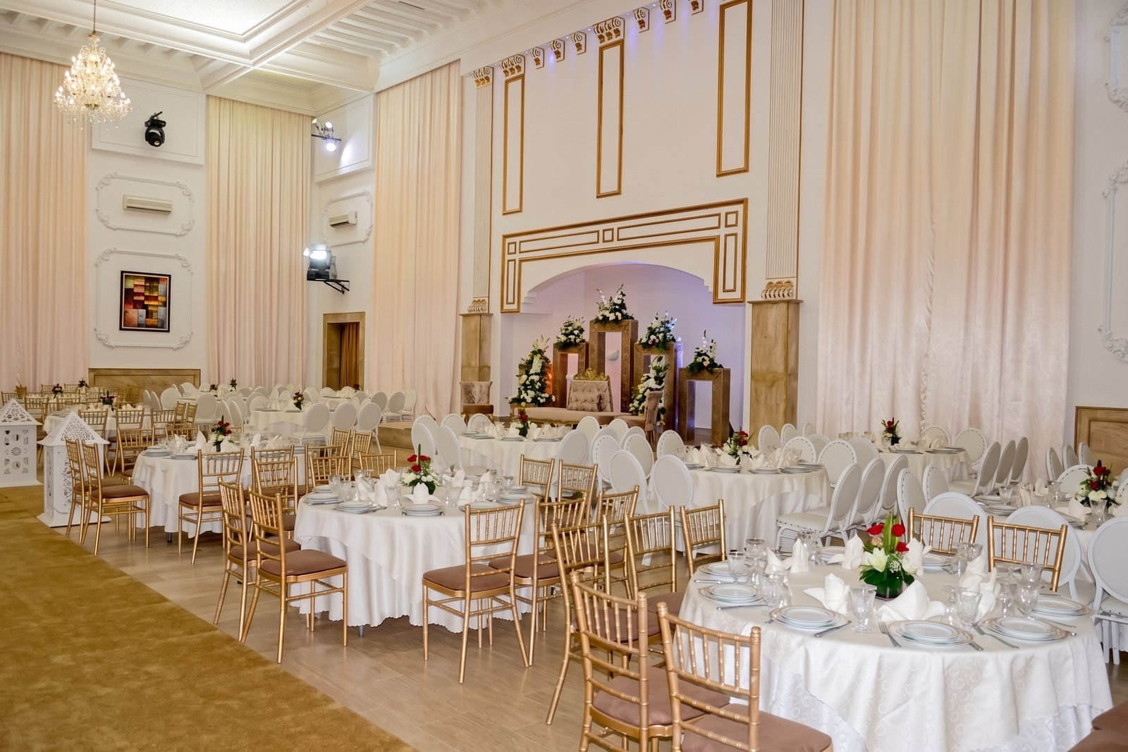 Salle de réception dressée avec des tables rondes et des chaises dorées