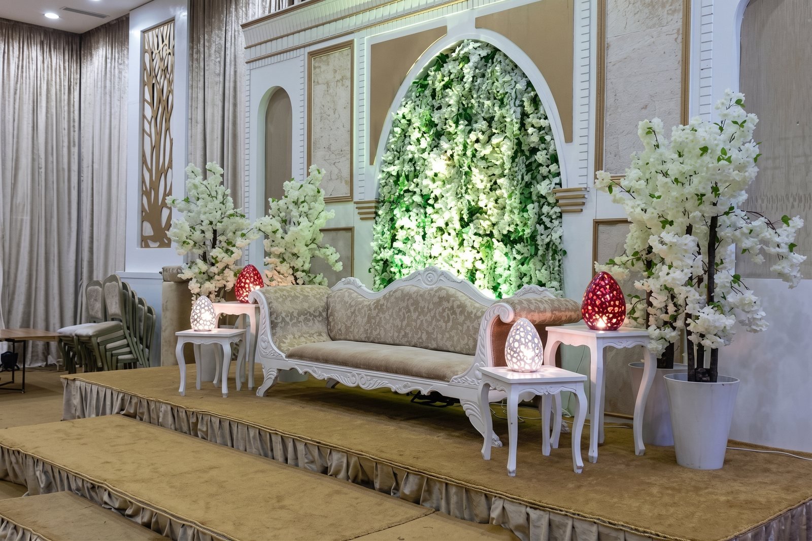 Salon décoré de fleurs blanches avec un canapé sur une estrade pour une soirée de fiançailles